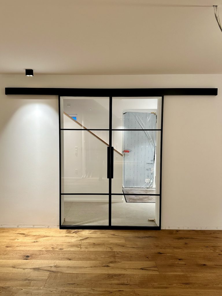 Doppelte Loft-Schiebetür mit Klarglas zwischen Wohnraum und Treppenhaus