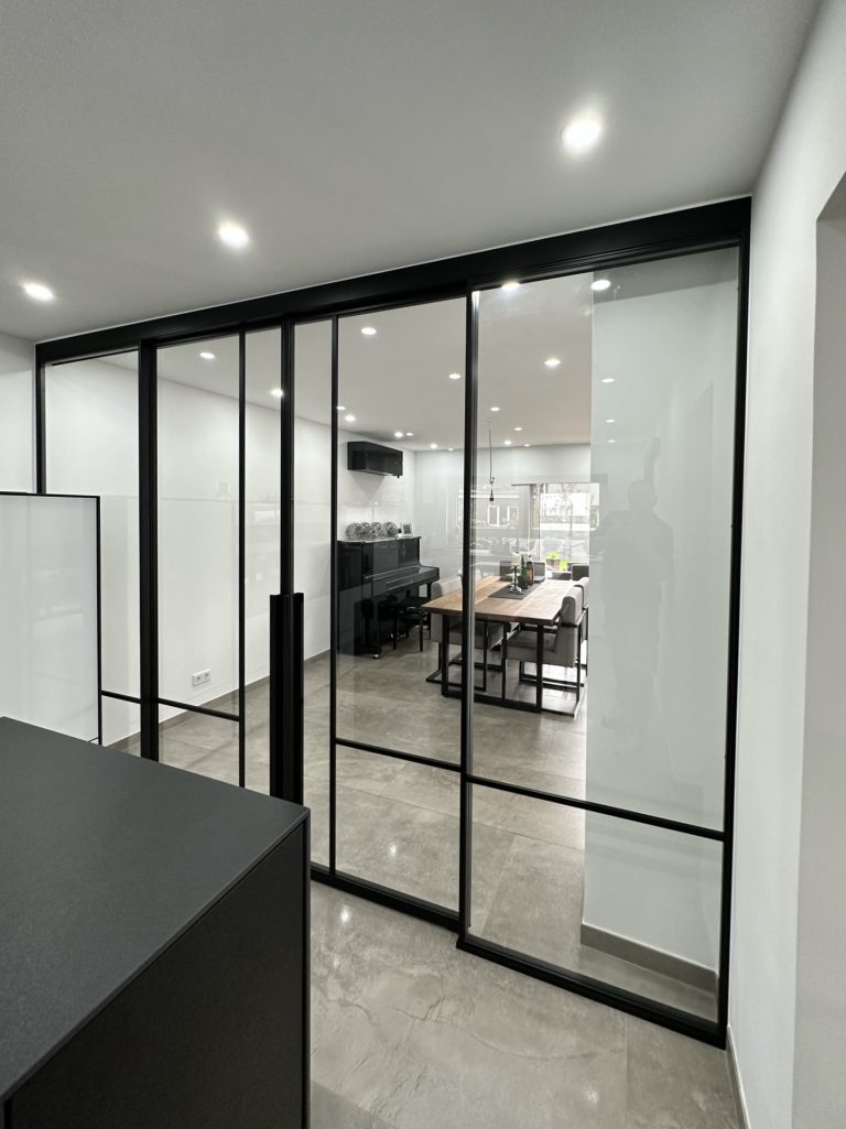 Raumteiler mit doppelflügeliger Schiebetür und zwei Fixelementen aus Klarglas