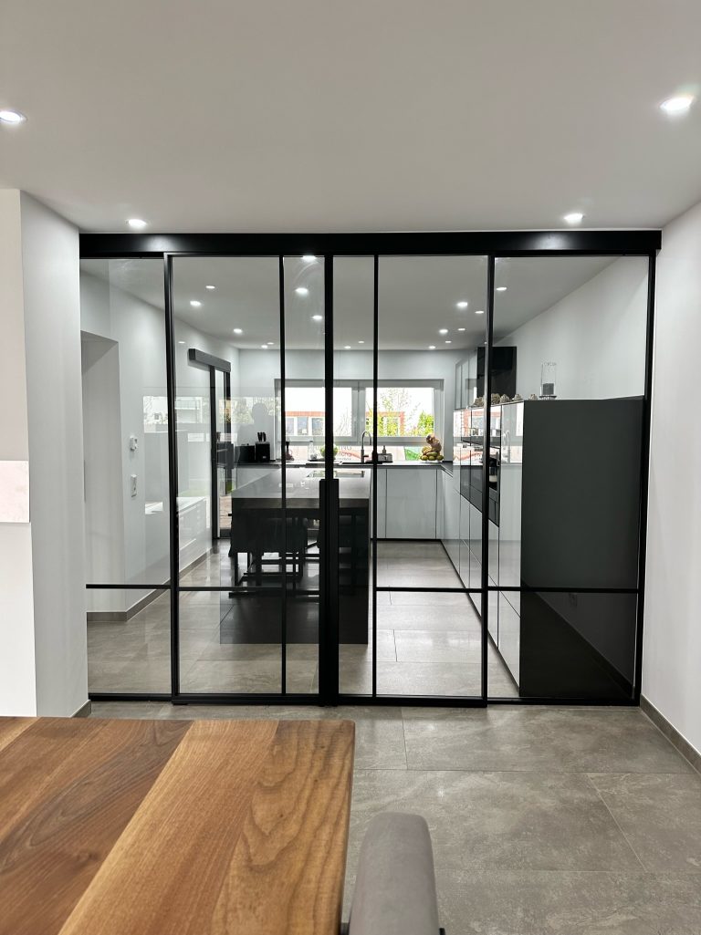 Raumteiler mit doppelflügeliger Schiebetür und zwei Fixelementen aus Klarglas