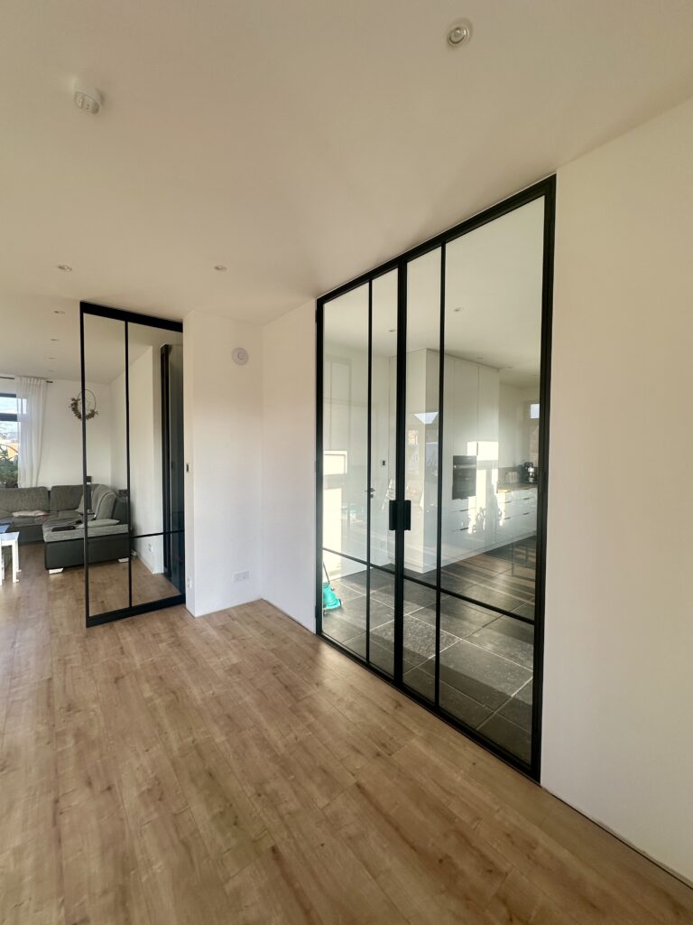 Lofttüren CROSS2 mit schwarzem Stahlrahmen RAL 9005 und Klarglas als Innentüren zur Küche und zum Wohnbereich