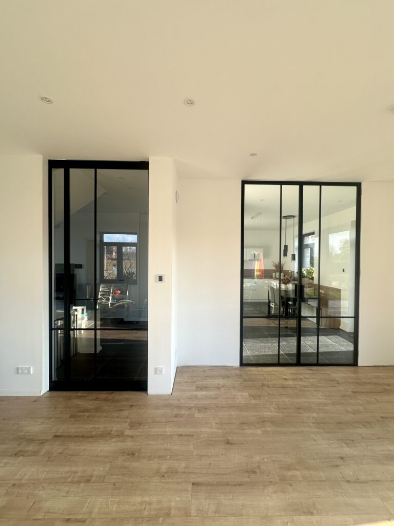 Lofttüren CROSS2 mit schwarzem Stahlrahmen RAL 9005 und Klarglas als Innentüren zur Küche und zum Wohnbereich