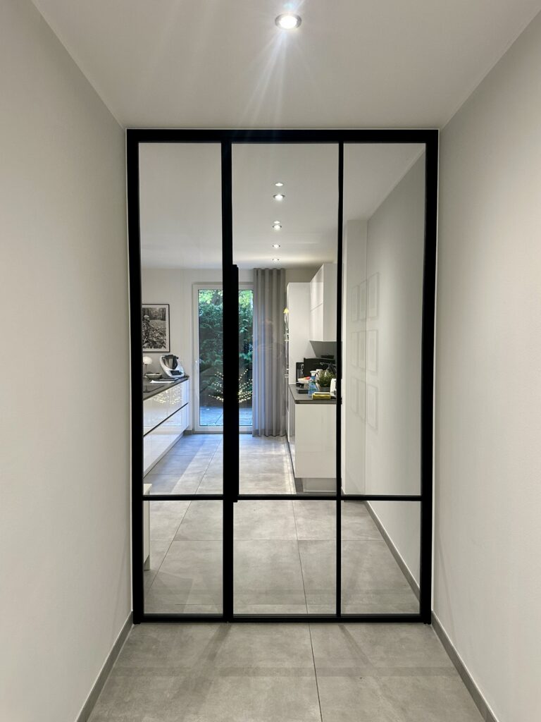 Klassische Loft-Drehtür mit Seitenteil im Windfang aus schwarzem Stahl RAL 9005 und Klarglas im Design CROSS