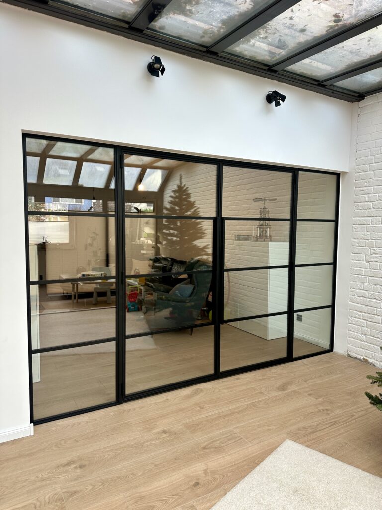 Raumteiler Lofttür als doppelflügelige Drehtür mit Seitenteilen aus schwarzem Stahl und Klarglas