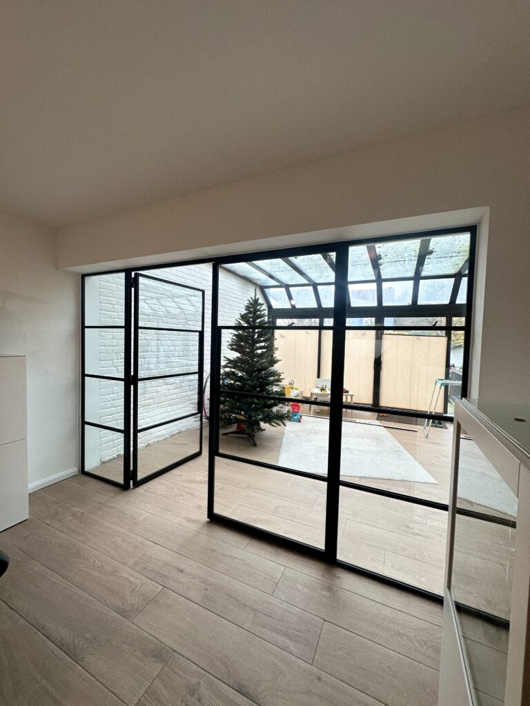 Raumteiler Lofttür als doppelflügelige Drehtür mit Seitenteilen aus schwarzem Stahl und Klarglas