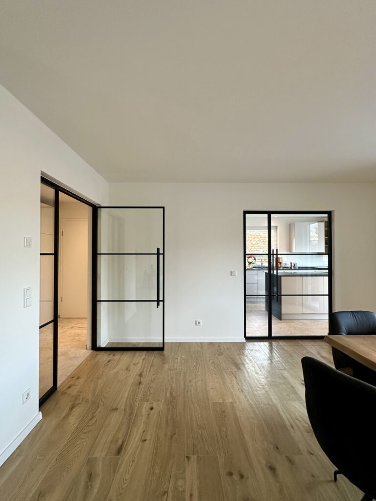 Lofttür Drehflügeltür mit fixem Seitenteil aus schwarzem Stahl und Klarglas im Wohnzimmer