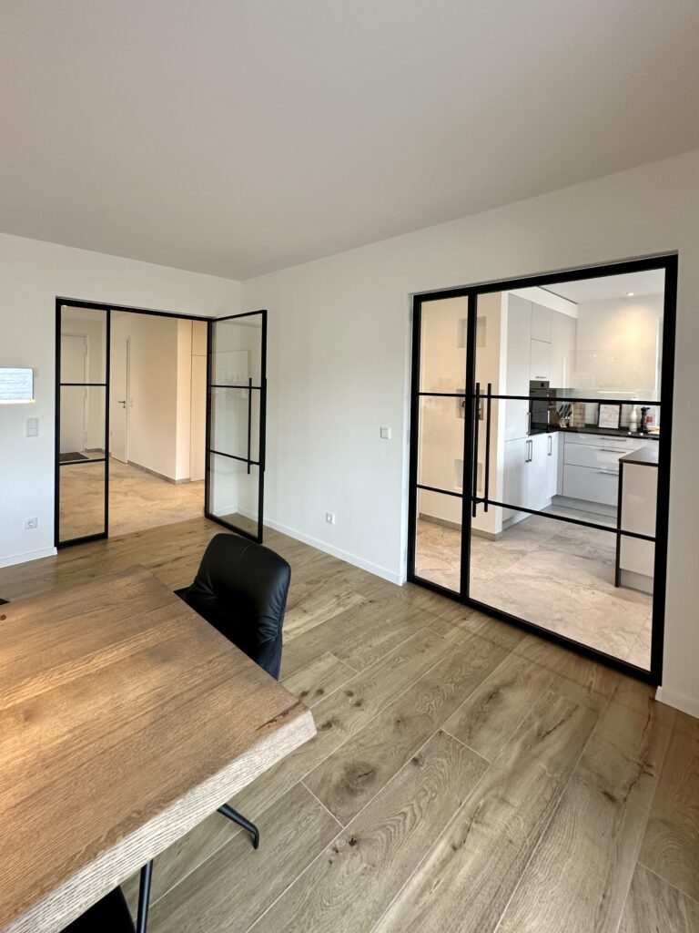 Lofttür Drehflügeltür mit fixem Seitenteil aus schwarzem Stahl und Klarglas im Wohnzimmer